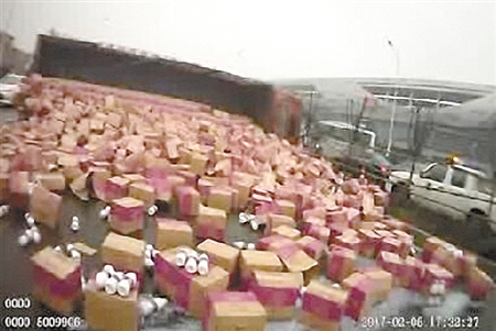 货车侧翻千余件奶制品落一地众人帮忙捡东西